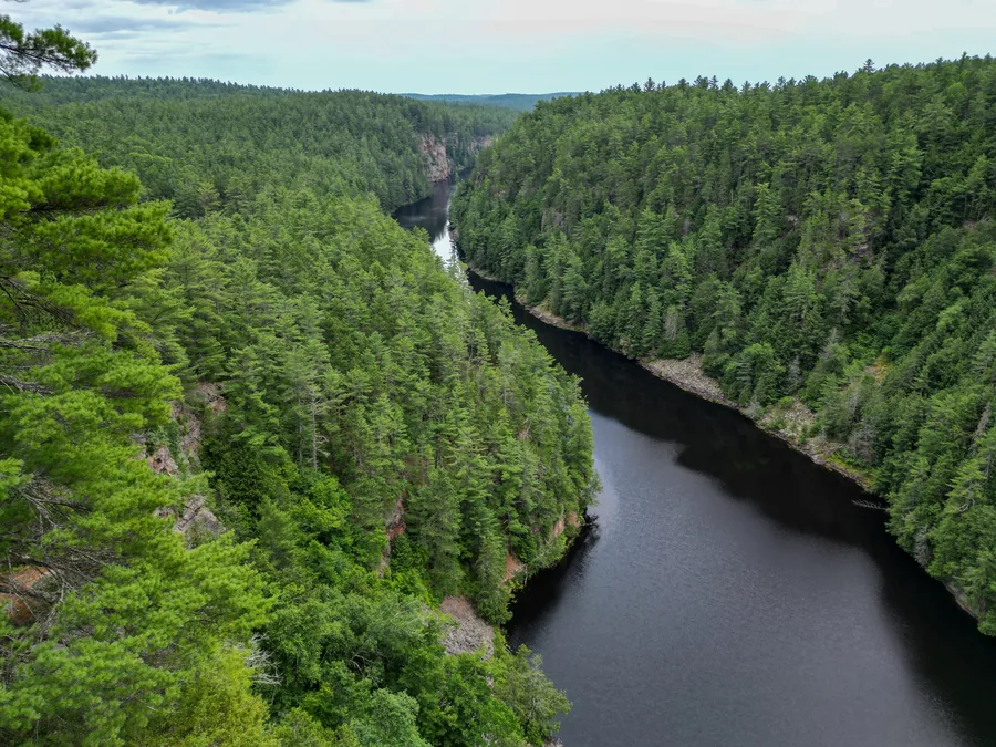 Une rivière encaissée entre des versants boisés, vue du ciel.