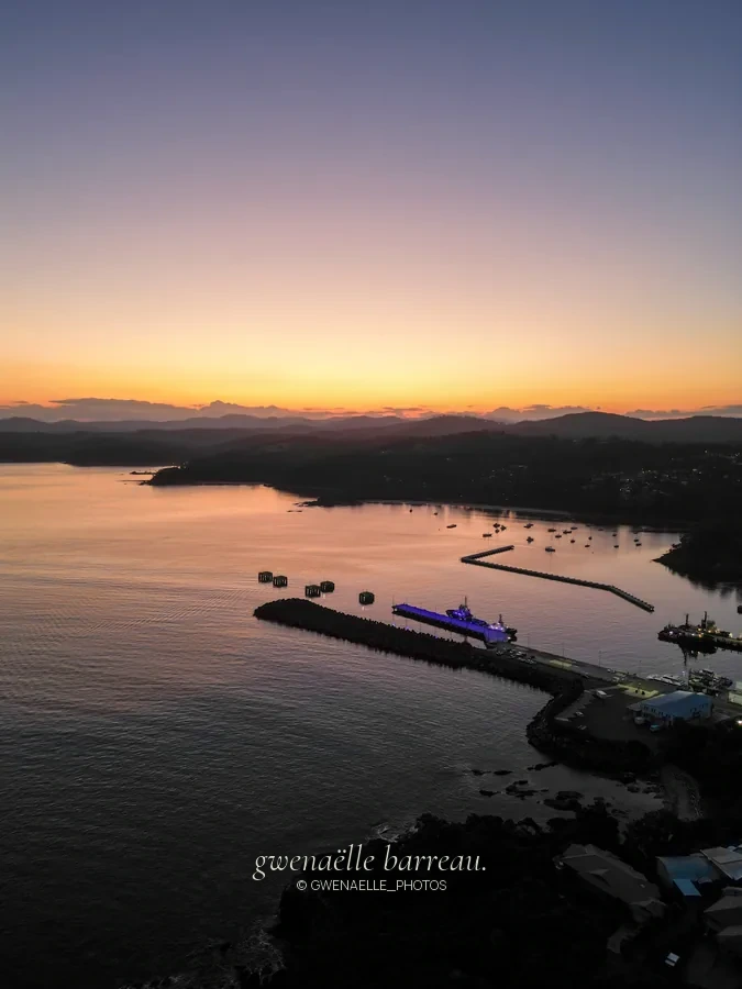 Port et embarcations sur une eau calme dans la lumière du crépuscule.