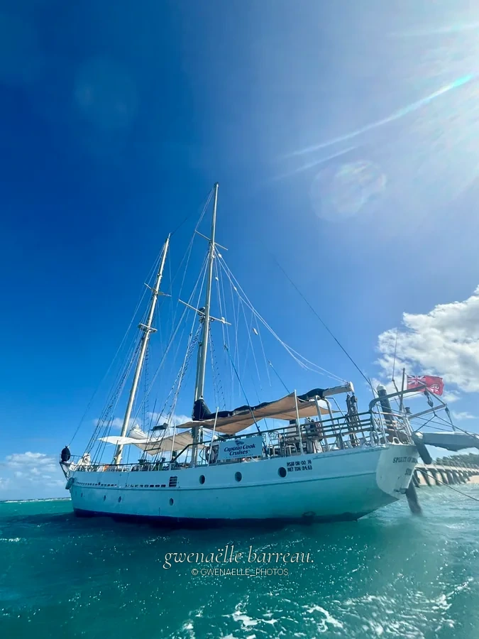 Voilier blanc amarré sur une eau turquoise sous le soleil.