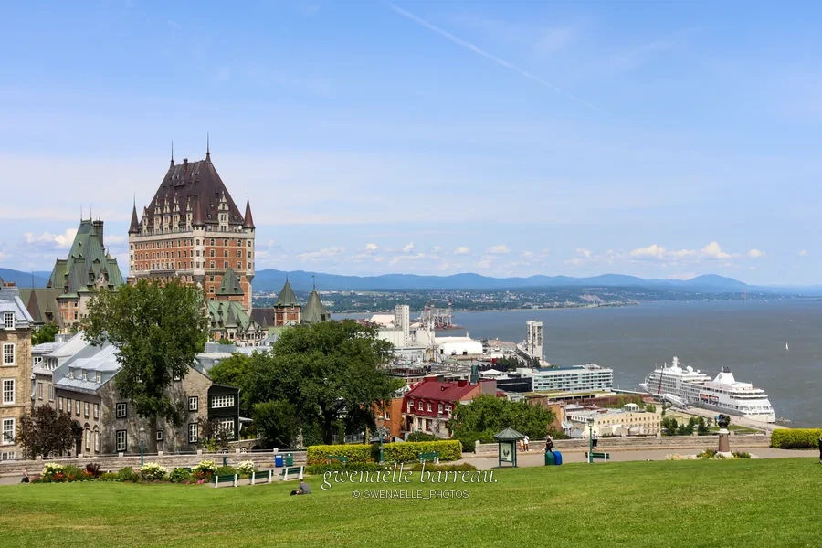 Grand édifice à tours au-dessus d'une ville, d'un fleuve et d'un navire.