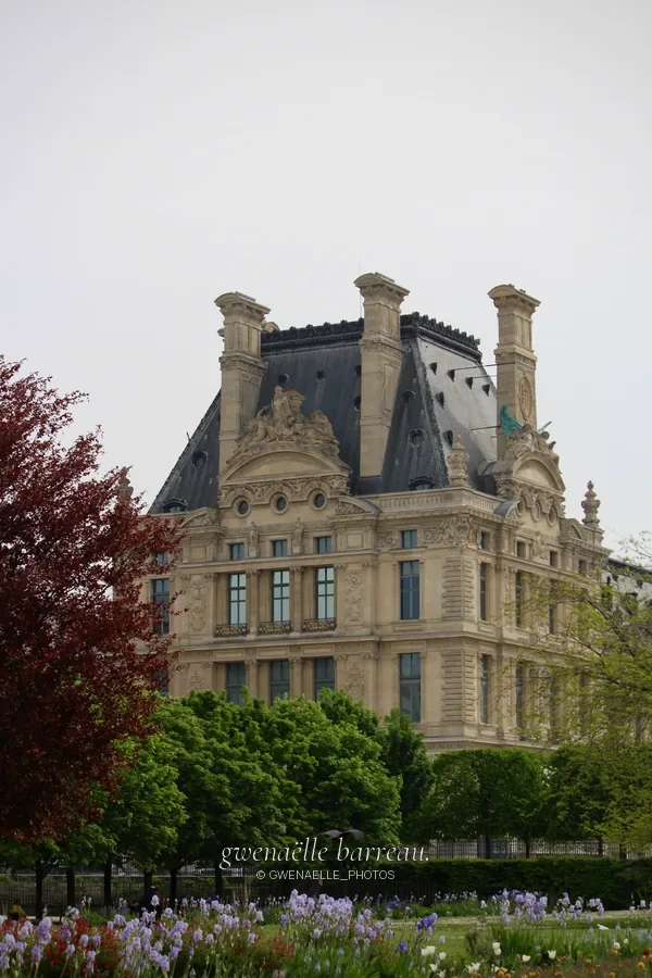 Pavillon de pierre orné de sculptures devant une rangée d'arbres.