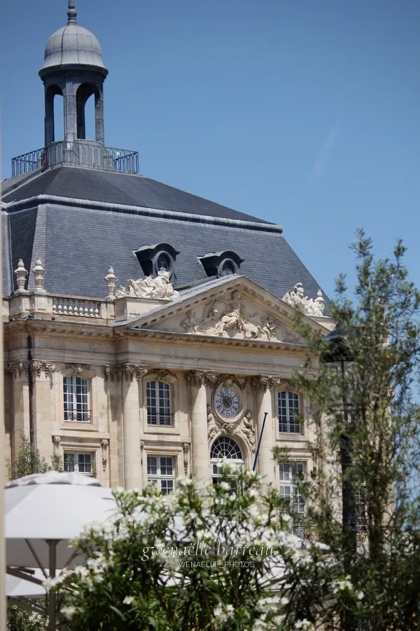 Façade de pierre à fronton sculpté sous une haute toiture sombre.
