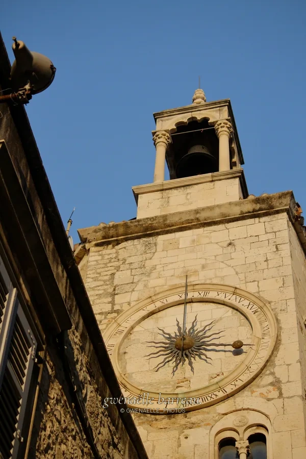 Tour de pierre avec une grande horloge ronde et une ouverture à cloche.