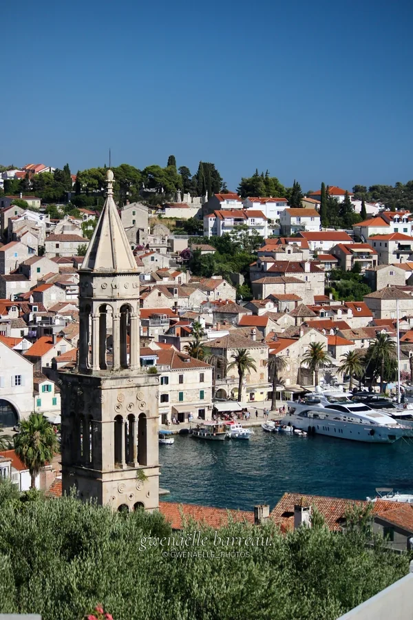 Clocher de pierre dominant les maisons serrées d'une ville portuaire.