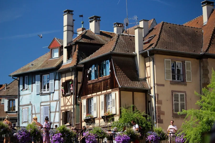 Maisons anciennes aux façades colorées et balcons fleuris au bord de l'eau.