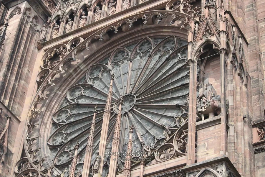 Grande rosace et sculptures détaillées d'une façade gothique.
