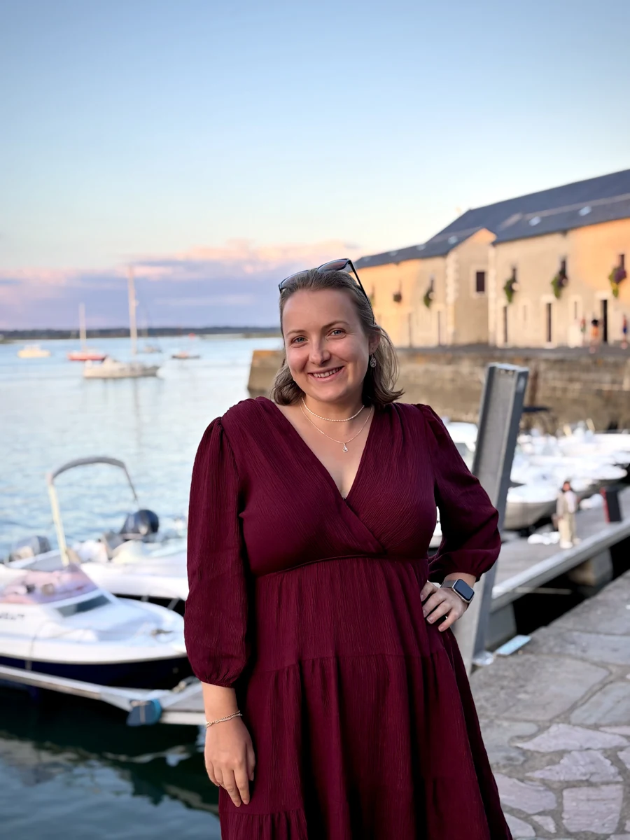 Gwenaëlle souriante au bord d’un port, dans la lumière du soir.